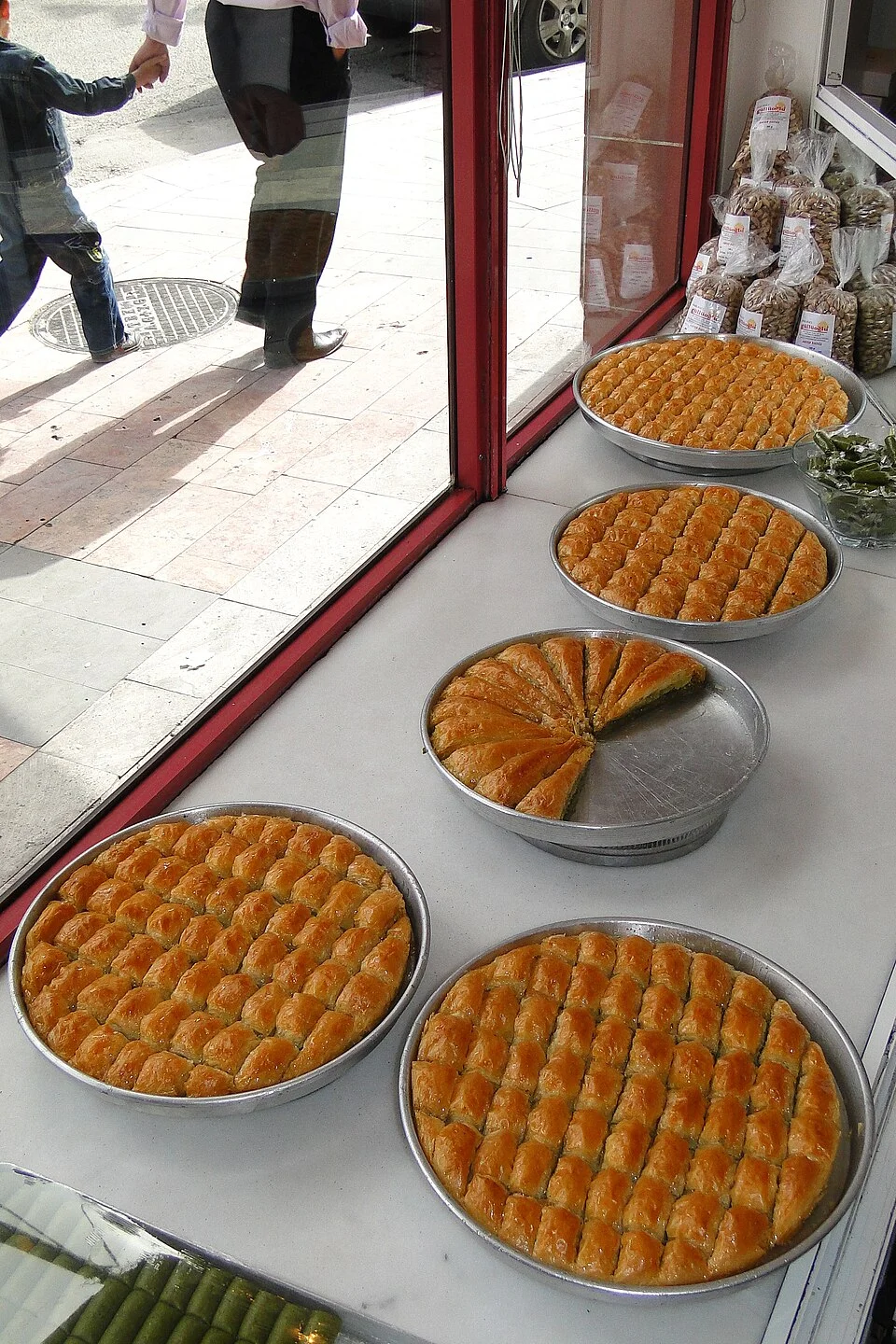 Gaziantep’te baklava tepsileri ve satış ortamı, Mayıs 2011; bugünkü stok veya aynı işletmenin faaliyeti iddiası değildir, kişiler şehir bağlamındadır.