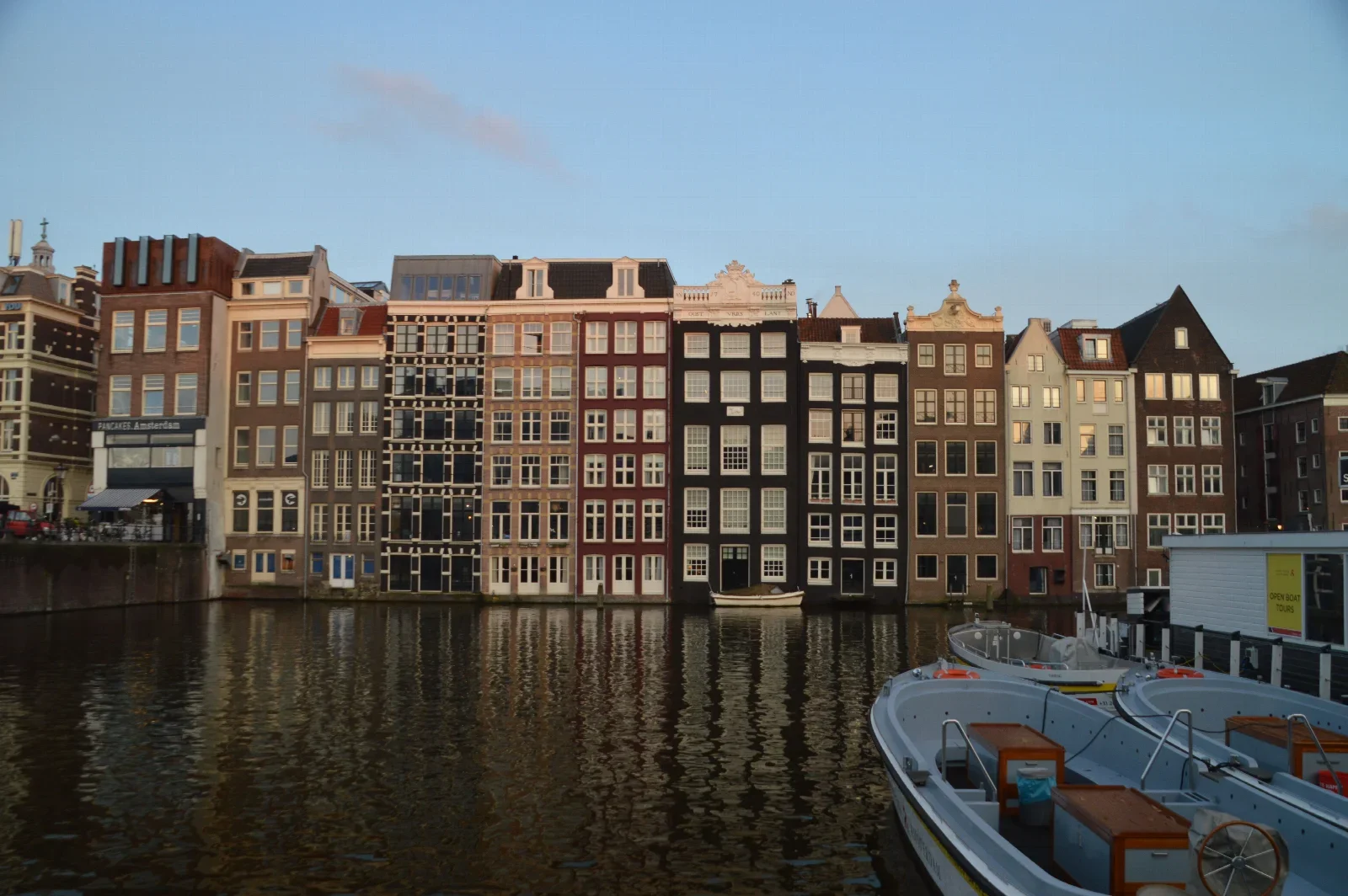 Amsterdam kanal evleri ve su yansımaları; yemek molaları arasındaki gerçek şehir bağlamı.