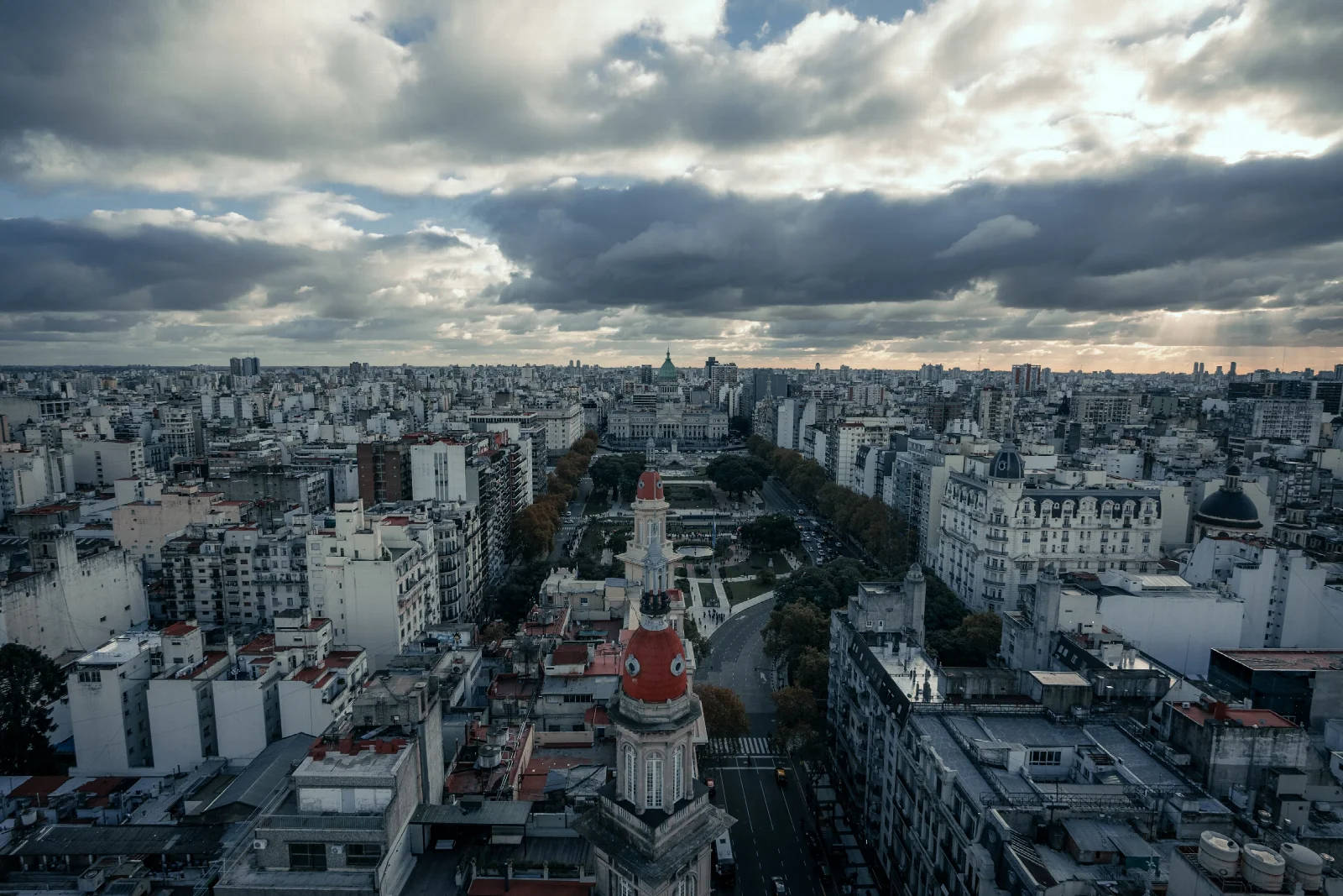 Buenos Aires’in üzerinde bulutlu gökyüzü, geniş bulvar ve farklı dönemlere ait şehir yapıları