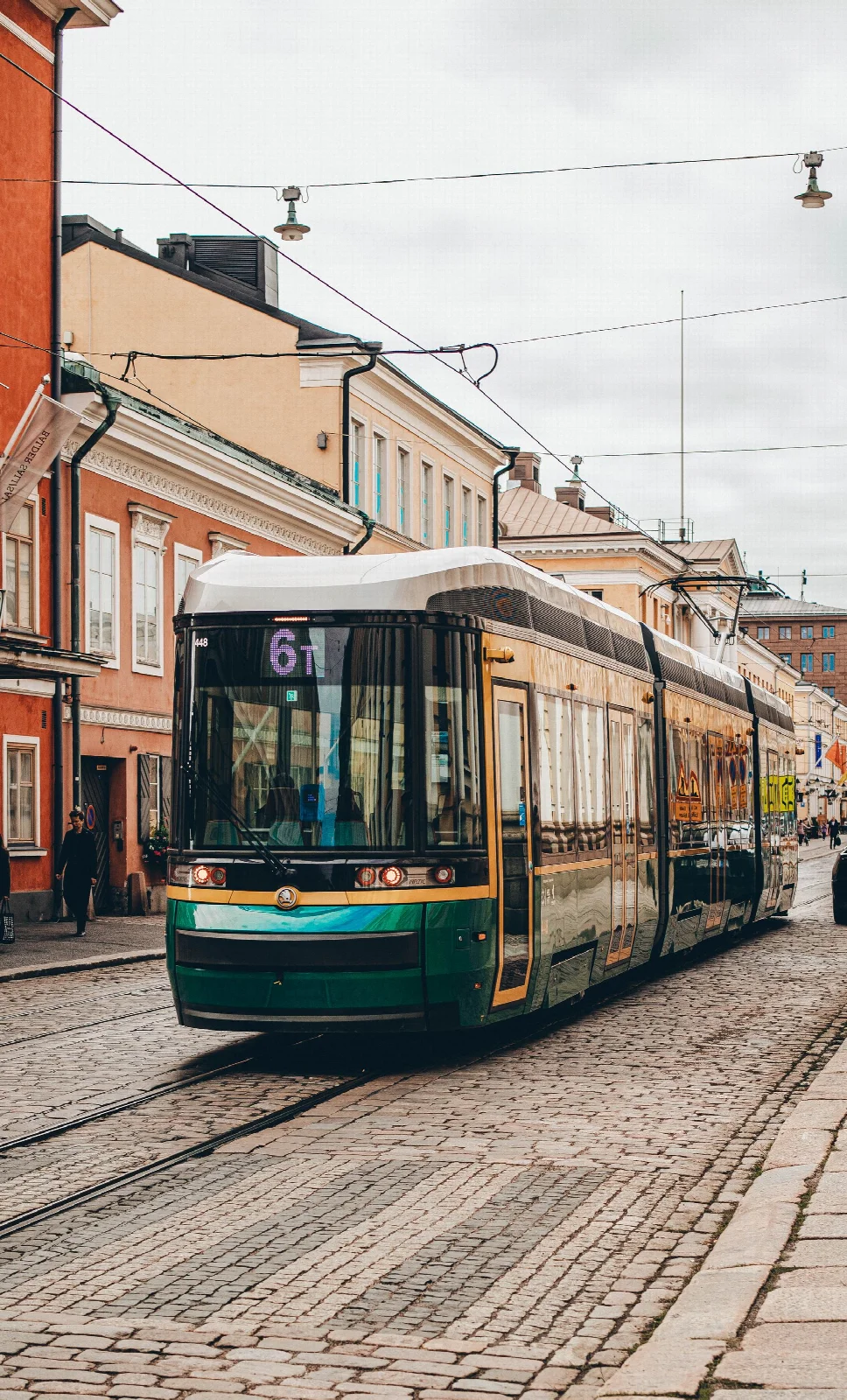 Helsinki’de taş döşeli caddeden geçen yeşil tramvay