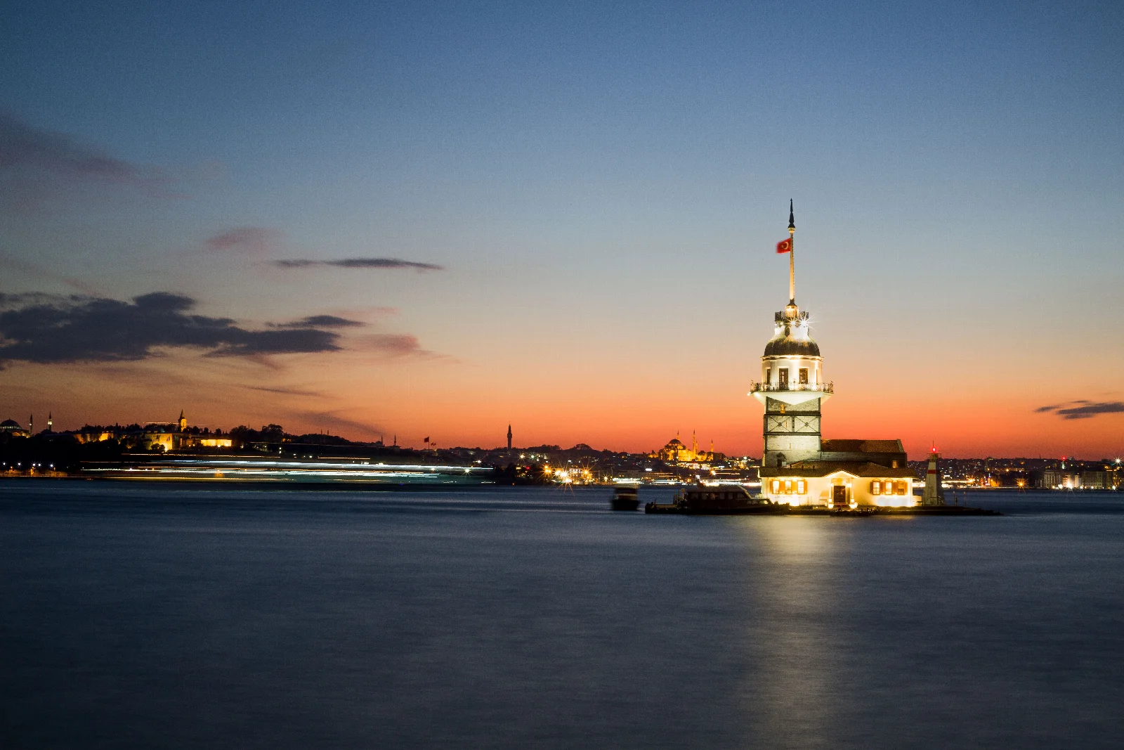 Akşam ışığında aydınlanan Kız Kulesi, sakin deniz ve turuncudan maviye dönen İstanbul gökyüzü