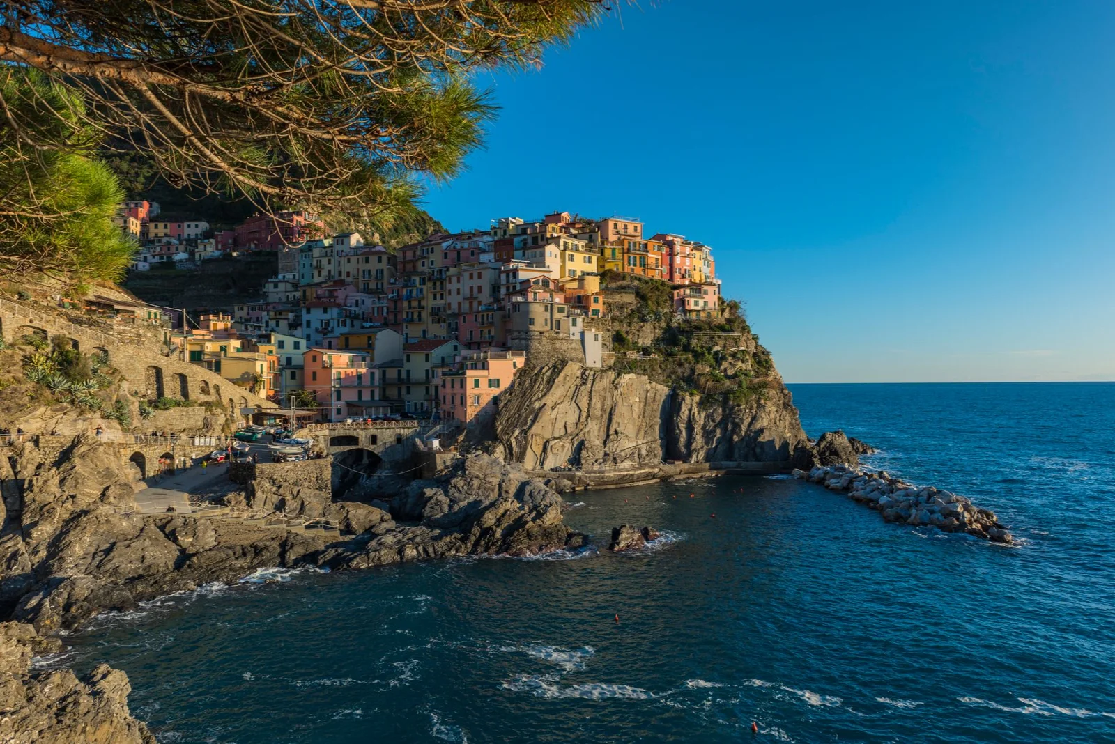 Manarola’da kayalık kıyının üzerinde renkli evler ve Ligurya Denizi