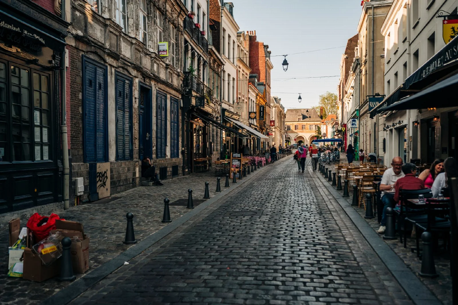 Historic buildings and restaurant tables on a cobbled street in Lille