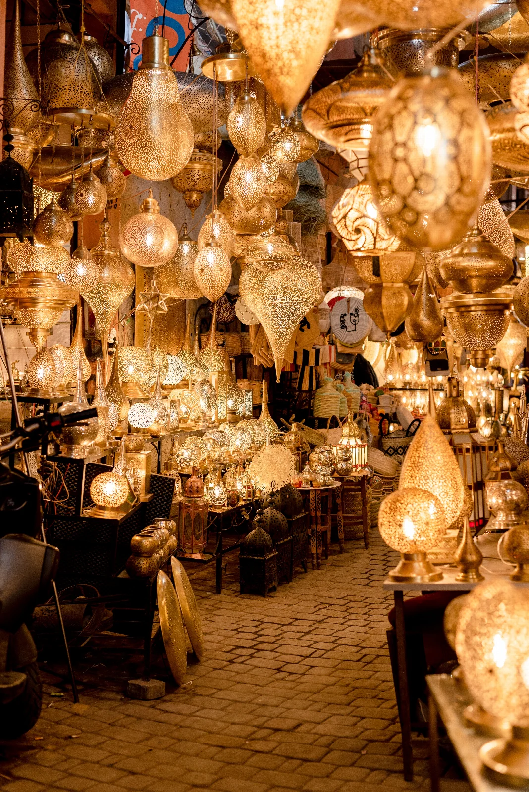 A Marrakech souk shop filled with glowing metal lanterns in different shapes and patterns
