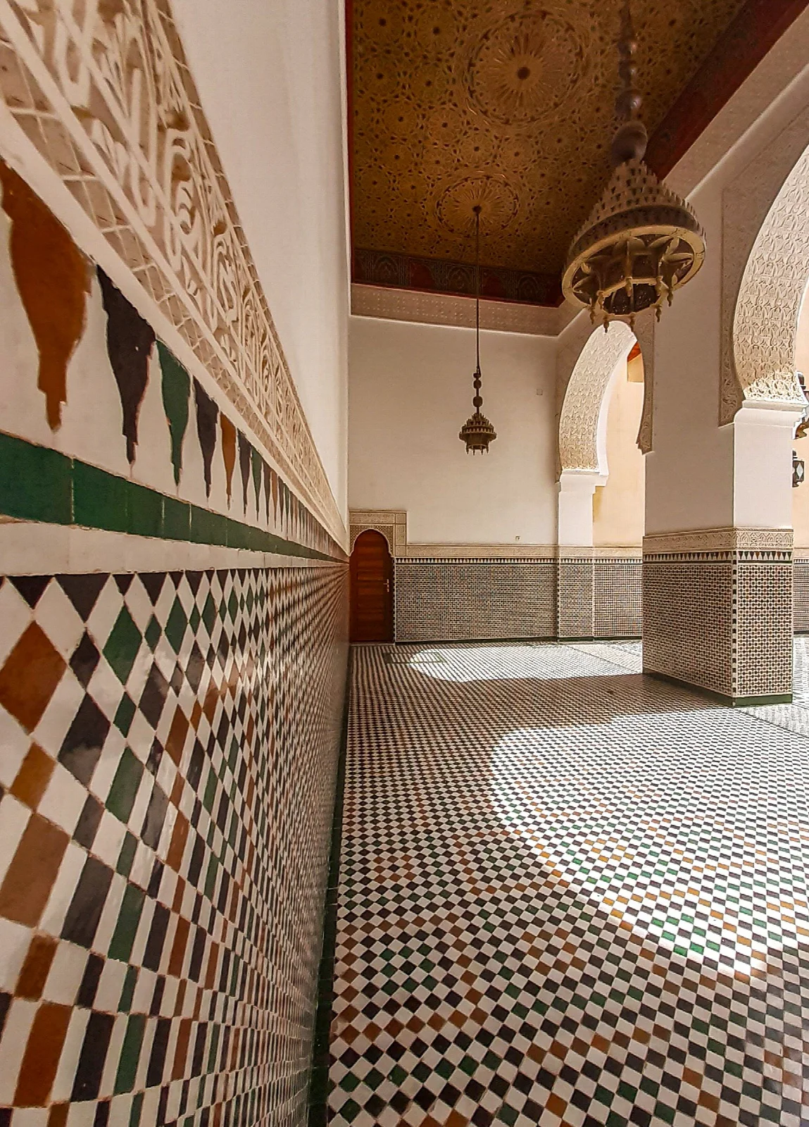 A Marrakech interior with geometric tiles, carved arches and a wooden ceiling