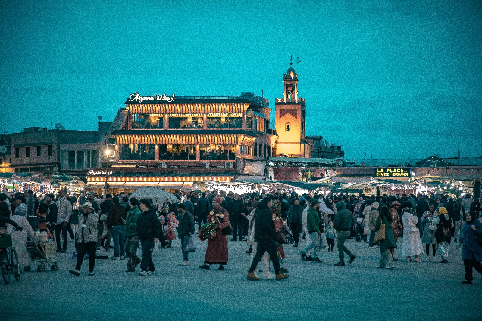 Evening crowds, illuminated terraces and a blue sky at Jemaa el-Fna square in Marrakech
