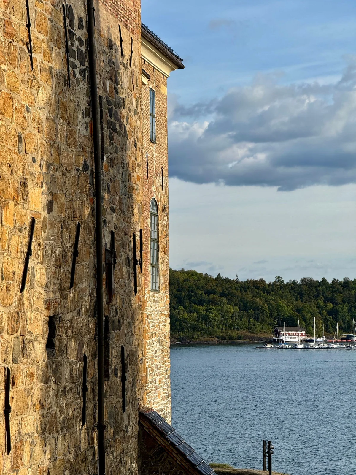 Stone walls of Oslo’s Akershus Fortress with the fjord and boats