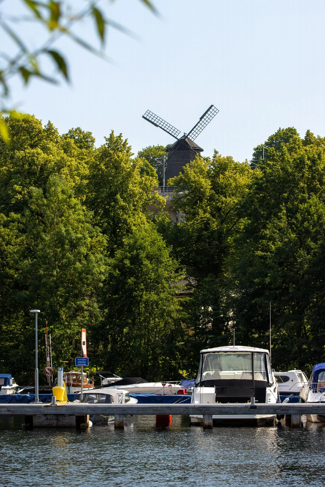 A historic windmill and a pier with boats on Stockholm’s Djurgården waterfront