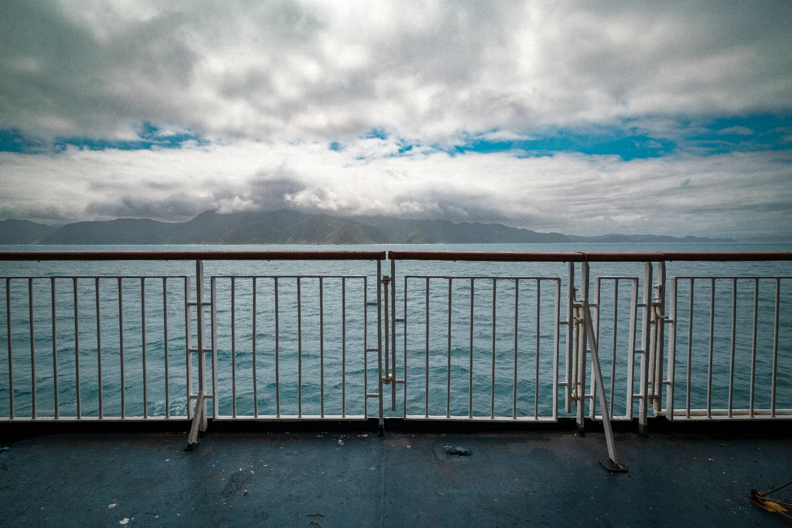 Hills across the water near Wellington, low clouds and a deck railing in the foreground